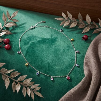 Sterling Ekatva silver heart charm necklace flat lay product photography on green velvet background with decorative leaves.